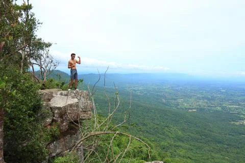 Man relaxing on top of a mountain and enjoying a valley view. Stock Photos