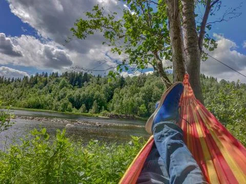 A man is relaxing under the tree shadow beside a river bank during the hiking Stock Photos