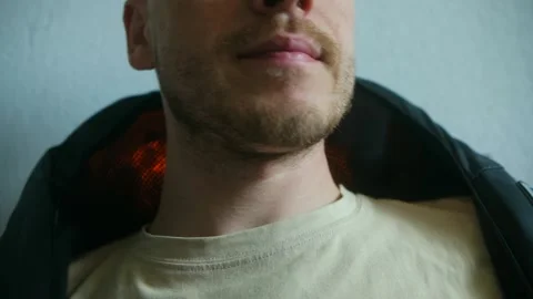 Man relaxing using electric neck massager at home Stock Footage 313642808