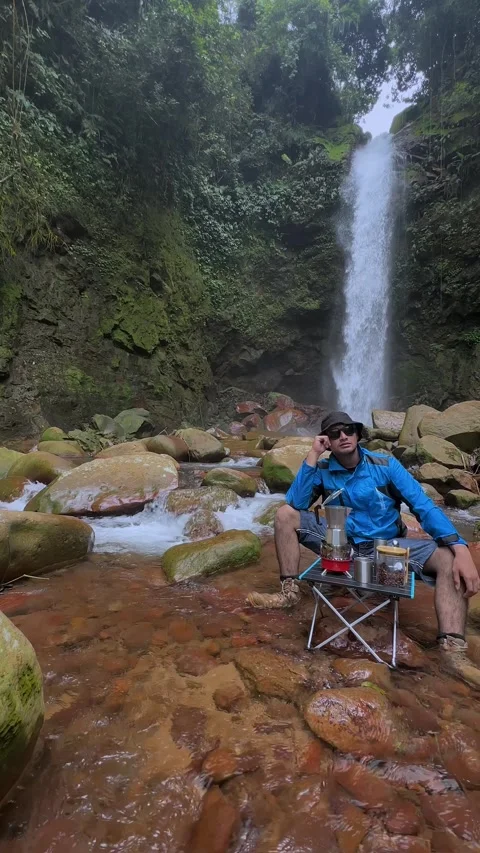 Man Relaxing by Waterfall, Drinking Coffee, Tropical Jungle Stream, Vertical Wid Stock Footage 321104379