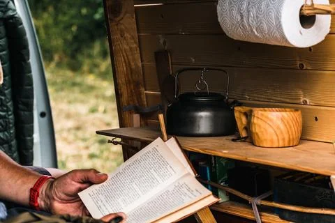 Man relaxing while reading in a converted van Stockfoto's