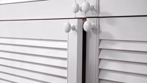 The man releases the handle of the cabinet door and it slowly closes. Close-up Vidéo 326777341