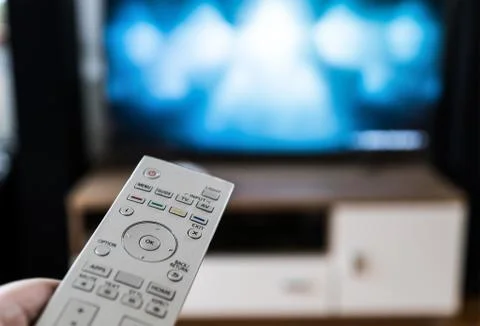 The man with the remote control in hand watching tv Stock-Fotos