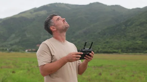 A man with a remote control in his hands looks up at sky searching for drone. Stock Footage 321727784