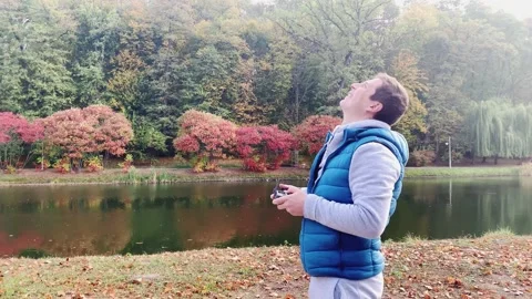 A man with a remote control looks into the sky, controlling the flight of a Vídeos de archivo 151744251