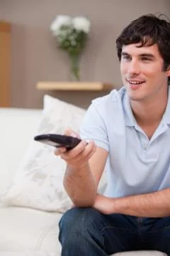 Man with remote control on the sofa Stock Photos