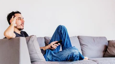 Man with remote control on sofe watching TV Stock Photos