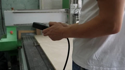 A man with a remote control turns on a program on a modern laser on wood. Stock Footage 287584473