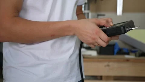 A man with a remote control turns on a program on a modern laser on wood. Stock Footage 291516409