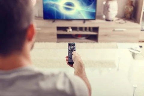 Man with remote control watching sci-fi at home in TV Stock Photos