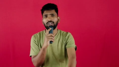 Man with remote singing pointing forward on red background Stock Footage 262362546