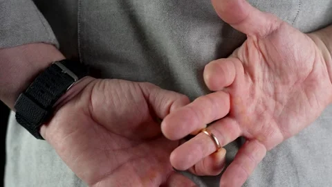 A man remove wedding ring from his finger holding hands behind his back, Stock Footage 264762595