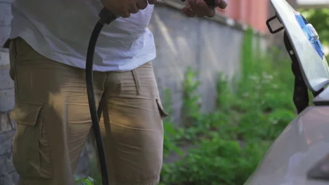 Man removes the electric car from the charge. He takes it out charging plug and Stock Footage 139041663
