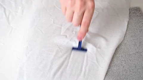 A man removes fabric pills using disposable shaving machine. A razor for Stock Footage 201517982