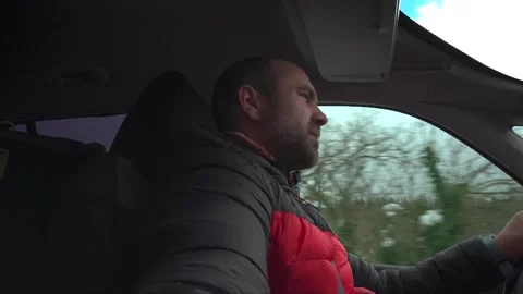 A man removes his winter hat while driving as he settles in for a long Stock Footage 148252155