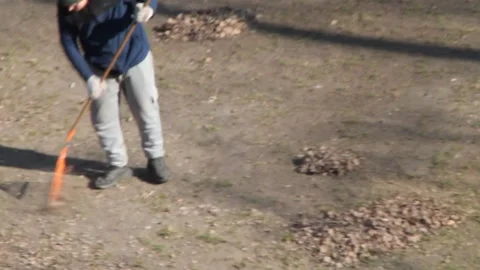 A man removes leaves from his plot with a rake in spring Vídeos de archivo 266502952