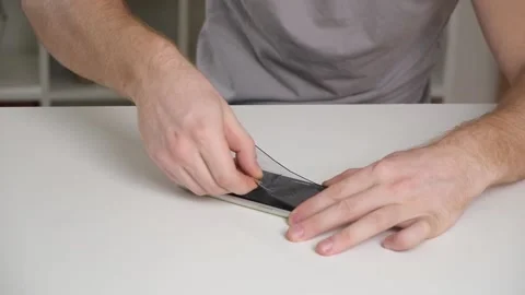 Man removes old cracked protective glass from phone. Broken glass iPhone XR Stock Footage 236423673