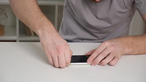 Man removes old cracked protective glass from phone. Broken glass iPhone XR Stock Footage 238501281