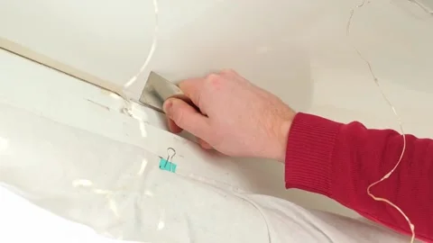 A man removes old, dried, dirty sealant with spatula between a window and a Stock Footage 169542753