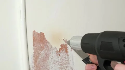 A man removes old white enamel paint from wooden door with a construction hair Video stock 178609446