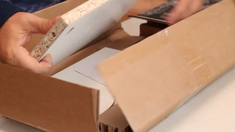 A man removes packaging from a table shelf. Elements of the prefabricated s.. Stock Footage 255385811