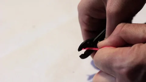 The man removes the red shell from the wire using forceps. Close-up. Stock Footage 80965524
