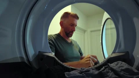 Man removing clean laundry from dryer, POV inside clothes dryer Vídeo Stock 345127014