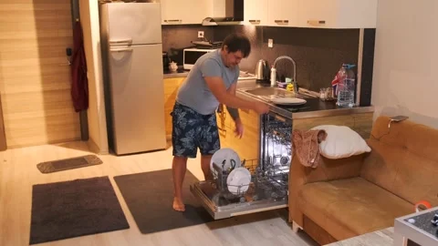 Man removing clean plates from dishwasher after washing cycle, unloading kitchen Stock Footage 333578594