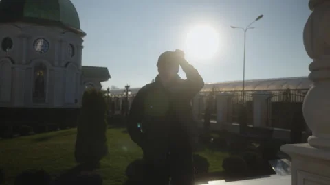 Man Removing Hat and Looking at Camera in Church Courtyard on Sunny Day Stock Footage 327013607