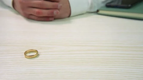 A man removing his wedding ring and placing it on the desk in front of him Stock Footage 299636128
