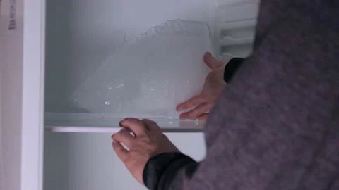 A man removing ice from refrigerator 库存影片 168571625