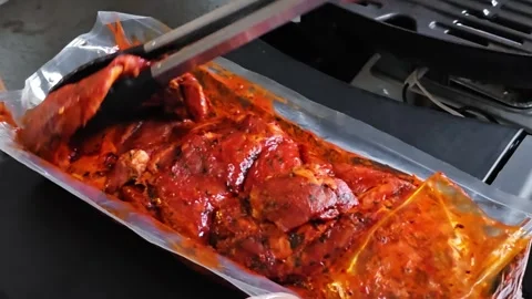 Man removing a marinated beef steak from its packaging and placing it onto .. Vidéo 345831794