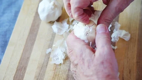 Man removing outer layers of garlic Stock Footage 77194096
