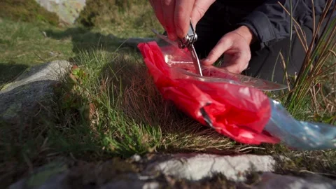 A man removing red meat, liver and beef from a packet outdoors Stock Footage 196749161