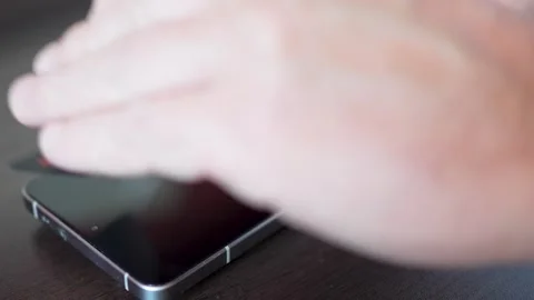 Man removing small dust from under smartphone screen protector with sticky .. Video stock 337895241