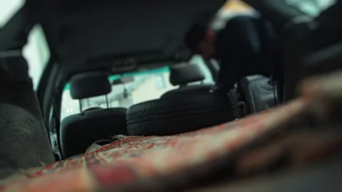 Man removing spare tire from car interior of estate wagon vehicle passenger 動画素材 323910897