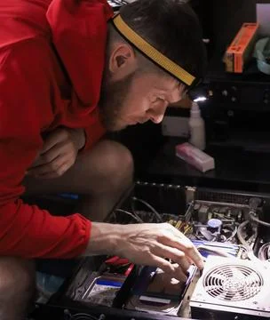 Man repairing computer hardware with flashlight in dark room Stock Photos