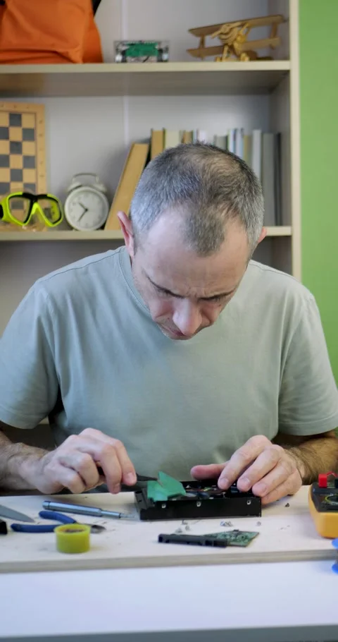 Man repairing electronic device with tools on table, focused hands-on process Stock Footage 344998694