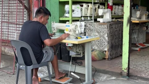 A man repairing an old sewing machine at a side street shop. Stock Footage 285295962
