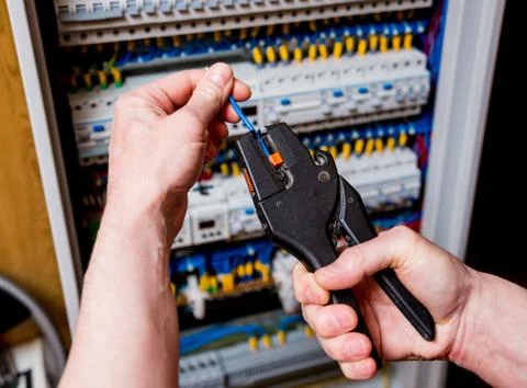 The man is repairing the switchboard voltage with automatic switches. Stock Photos