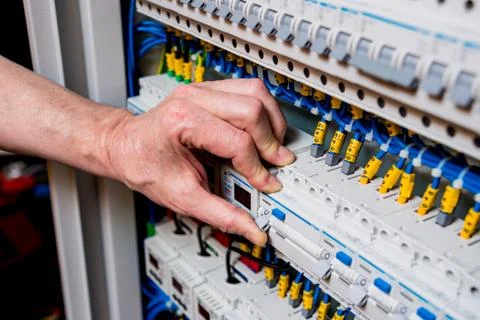 The man is repairing the switchboard voltage with automatic switches. Stock Photos