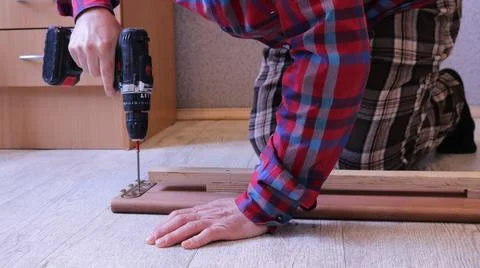 A man repairs a bed at home using a screwdriver Stock-Fotos