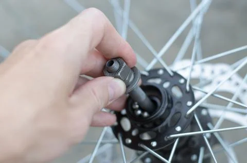 A man repairs a bicycle wheel. Replacement of bearings on the front wheel. Stock Photos