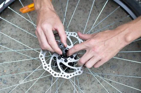 A man repairs a bicycle wheel. Replacement of bearings on the front wheel. Stock Photos