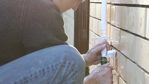A man repairs a broken tap on the territory of the dacha. Video stock 154408244