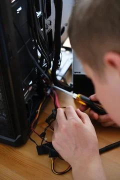 A man repairs a cable in a system unit and connects electrical wires 库存照片