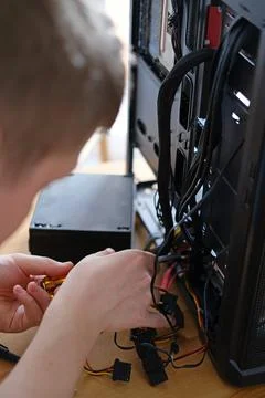 A man repairs a cable in a system unit and connects electrical wires 스톡 사진