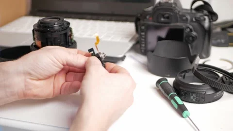 Man repairs camera lens, autofocus motor, tools. Screws in small screws with Stock-Footage 168375670