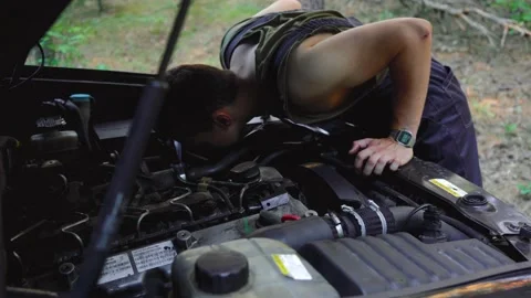 A man repairs a car that broke down in the woods Stock Footage 136820913
