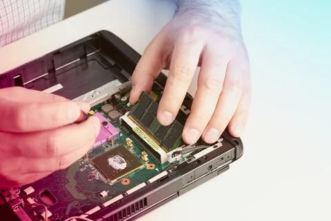 Man repairs computer. A service engineer in shirt repairs laptop, at white .. Stock Photos